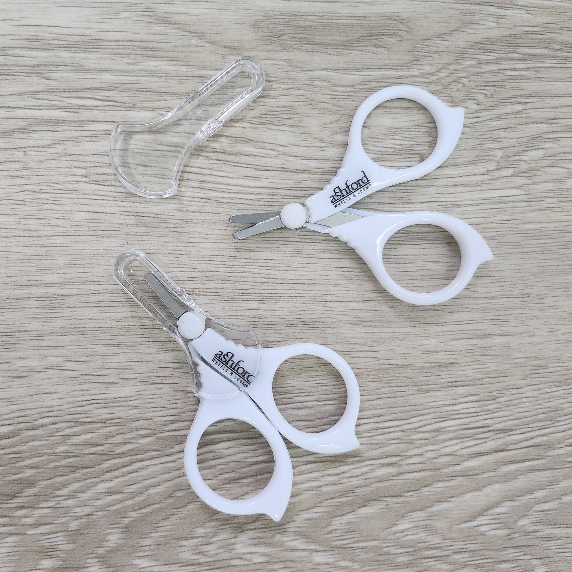 Pair of white Ashford Little scissors on a wooden surface
