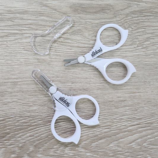 Pair of white Ashford Little scissors on a wooden surface