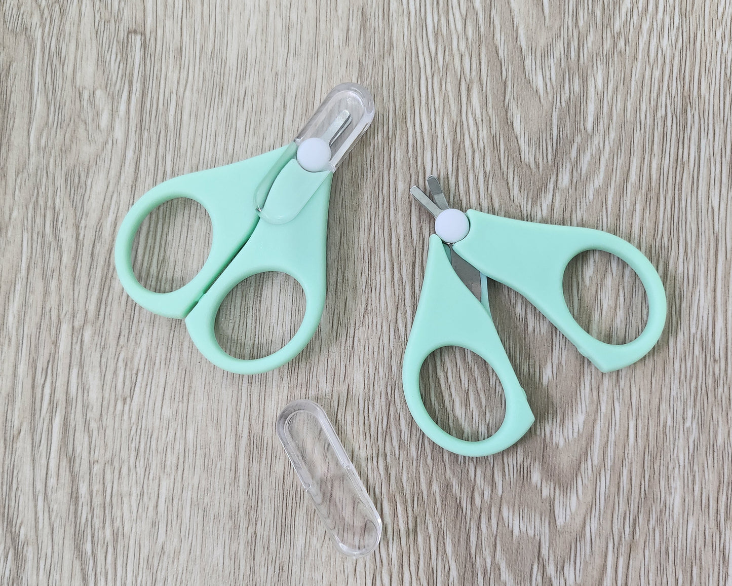 Two pairs of cyan small scissors on a wooden surface