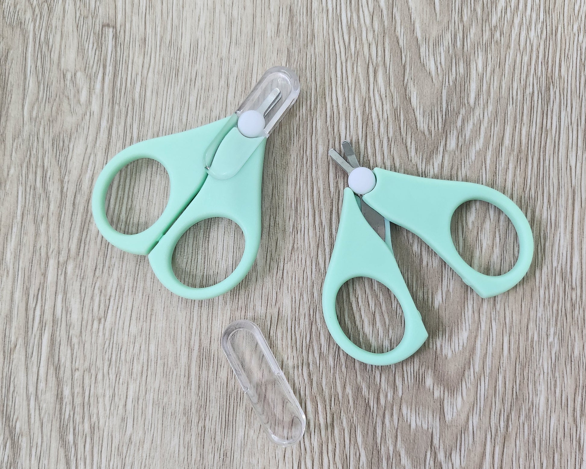 Two pairs of cyan small scissors on a wooden surface