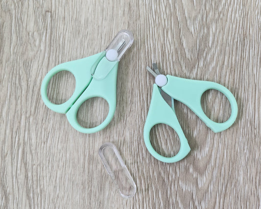 Two pairs of cyan small scissors on a wooden surface