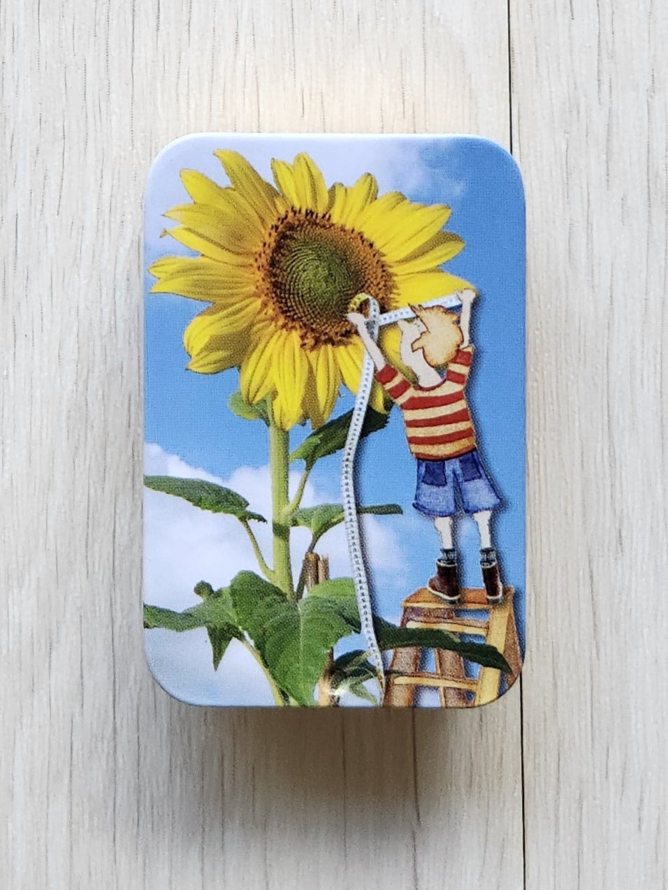 Small tin with a sunflower design on a white textured surface