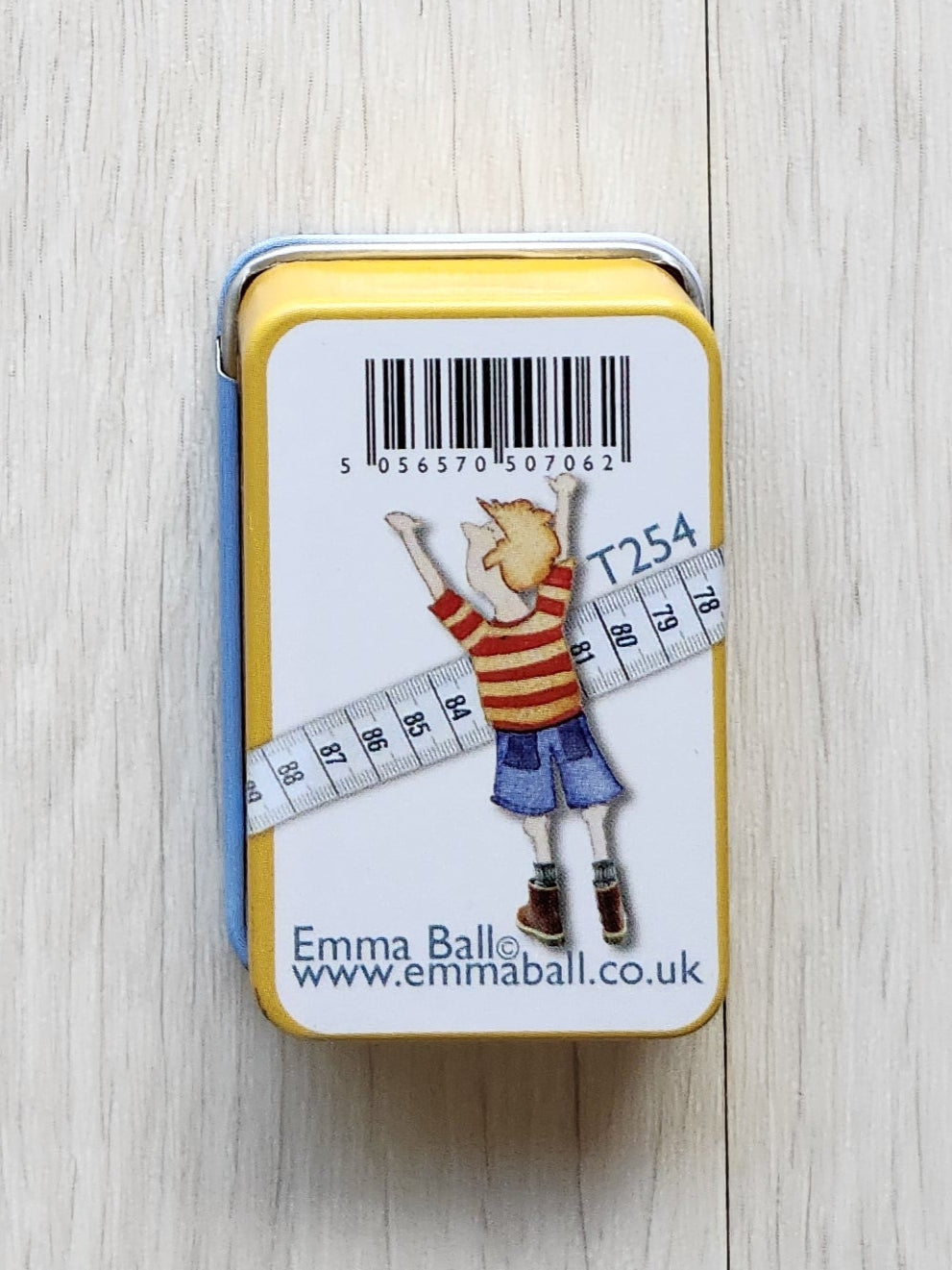 Small tin box with a label on a textured white surface