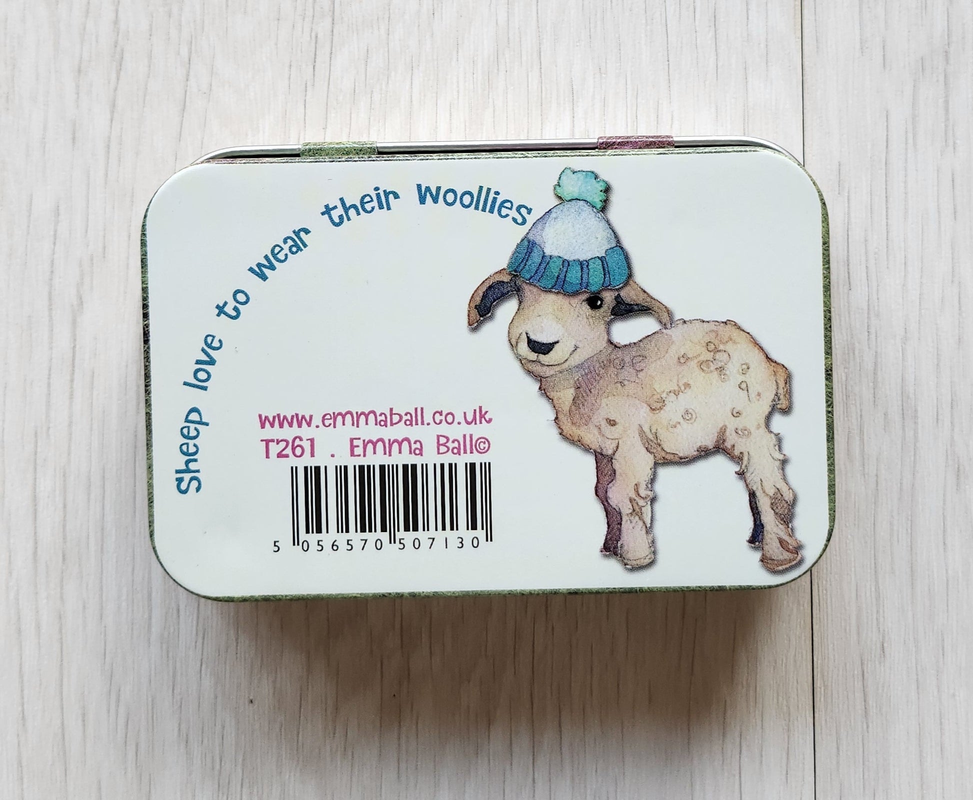 Small rectangular tin with cartoon character design on a light wooden surface emma ball hinged notions tin