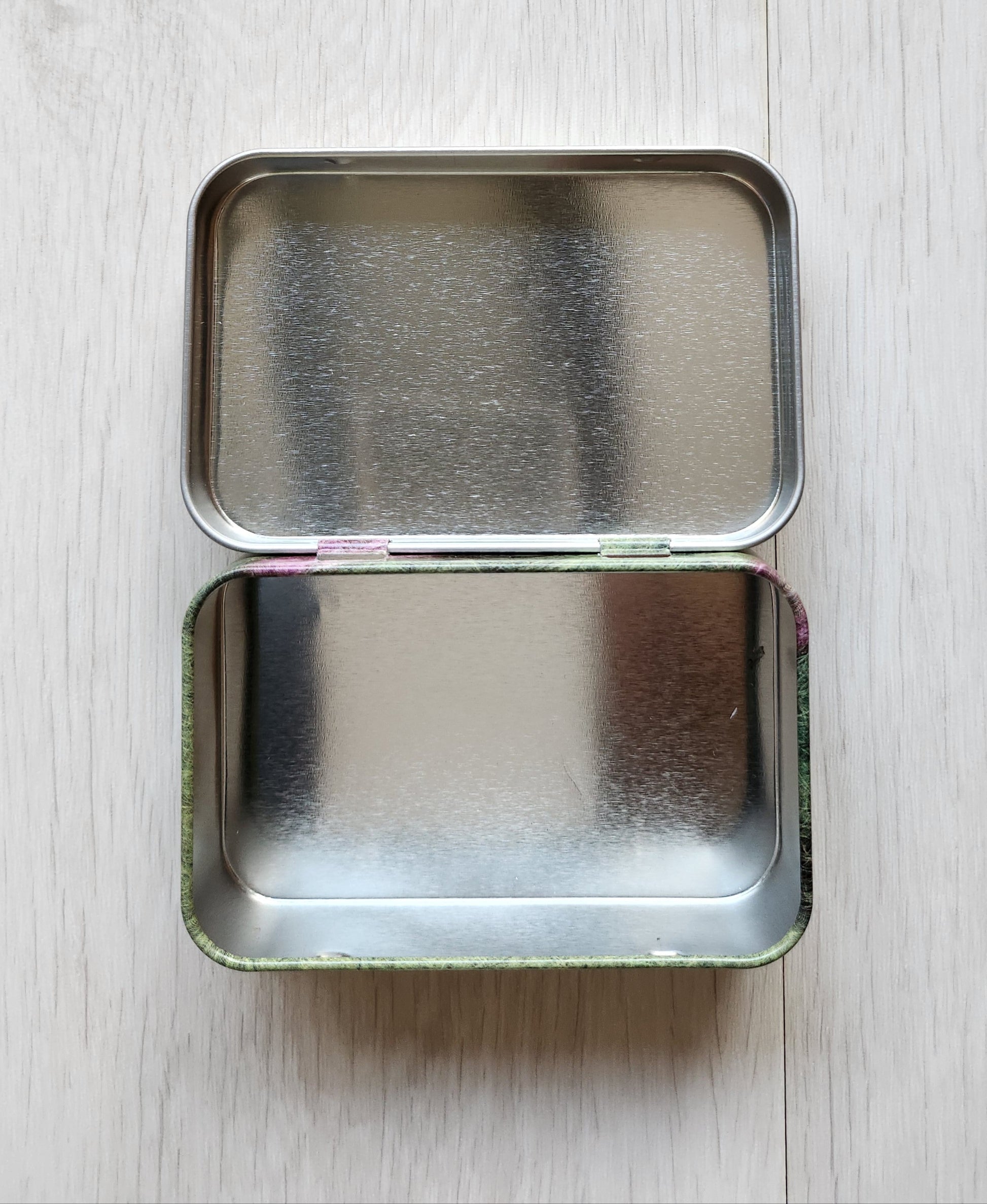 Small rectangular tin with cartoon character design on a light wooden surface emma ball hinged notions tin