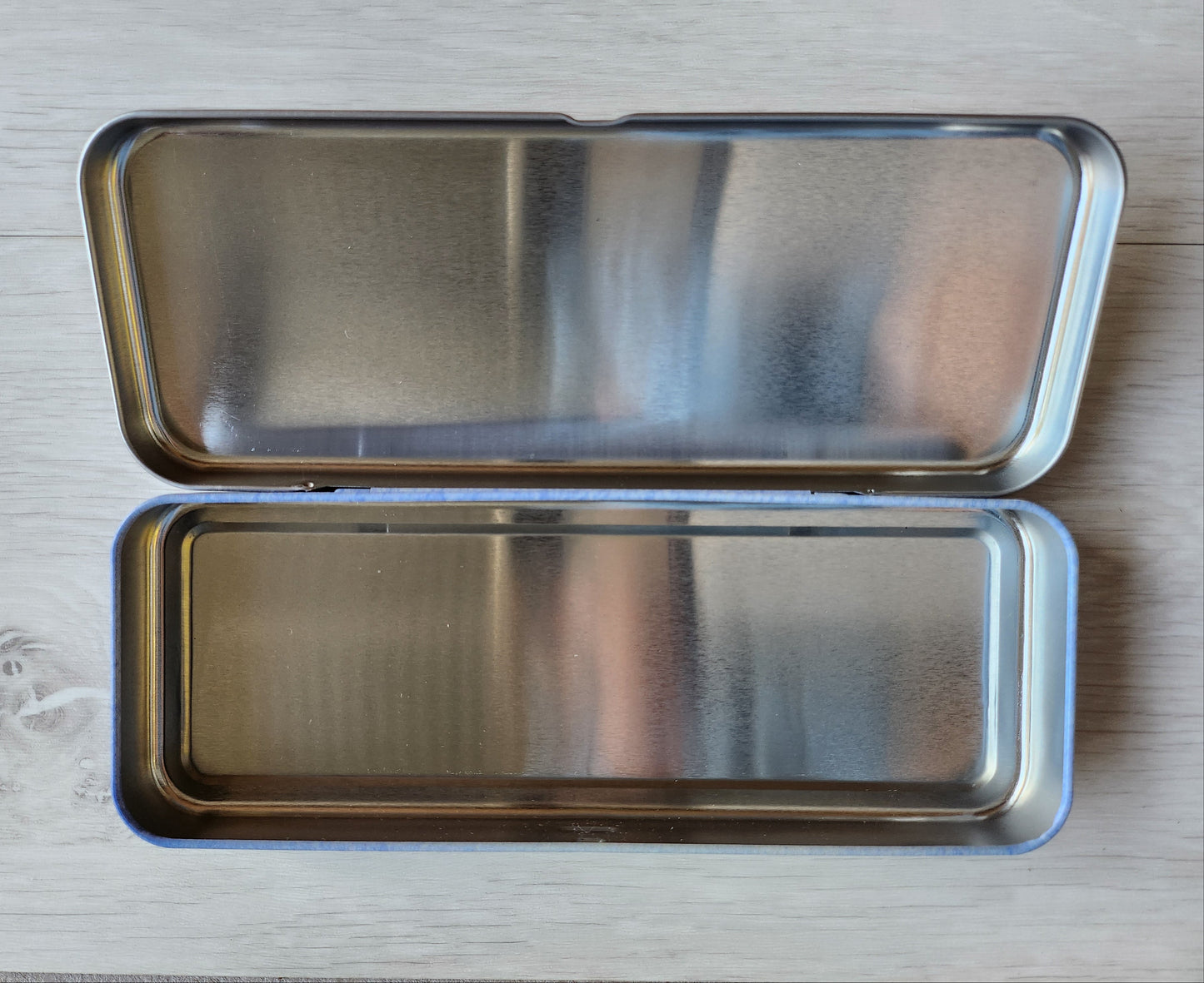 Metallic rectangular case with a lid on a light wooden surface emma ball