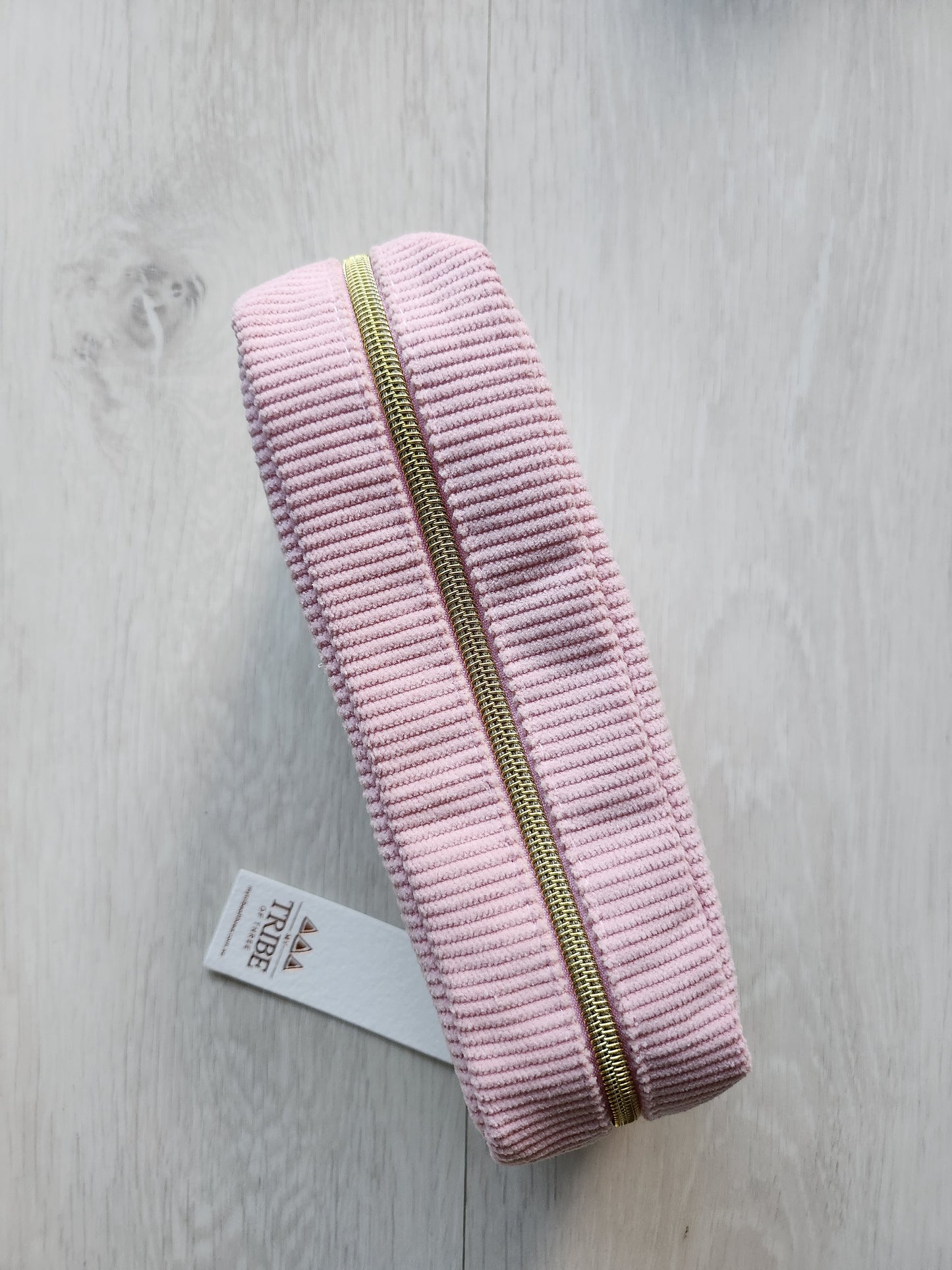 Pink pouch with gold zipper on a light gray background