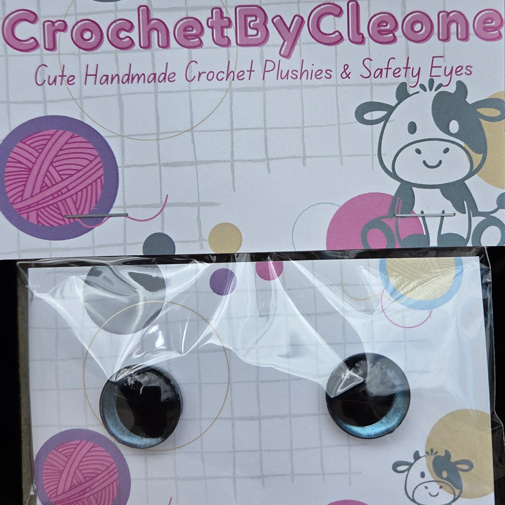 Two packages of CrochetByCleone handmade crochet crochet plushies and safety eyes, displayed on a rustic wooden surface.