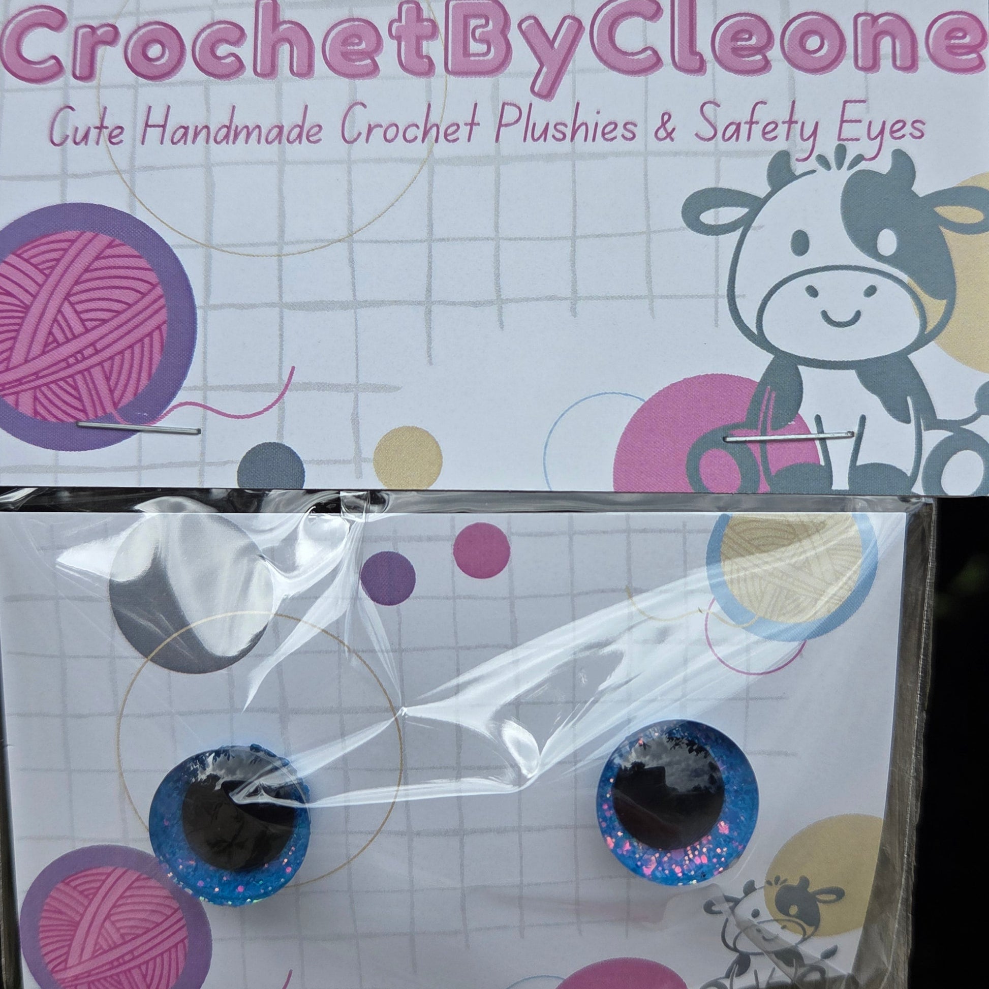 CrochetByCleo handmade crochet crochet plushies and safety eyes, shown with the product packaging on a rustic wooden surface.
