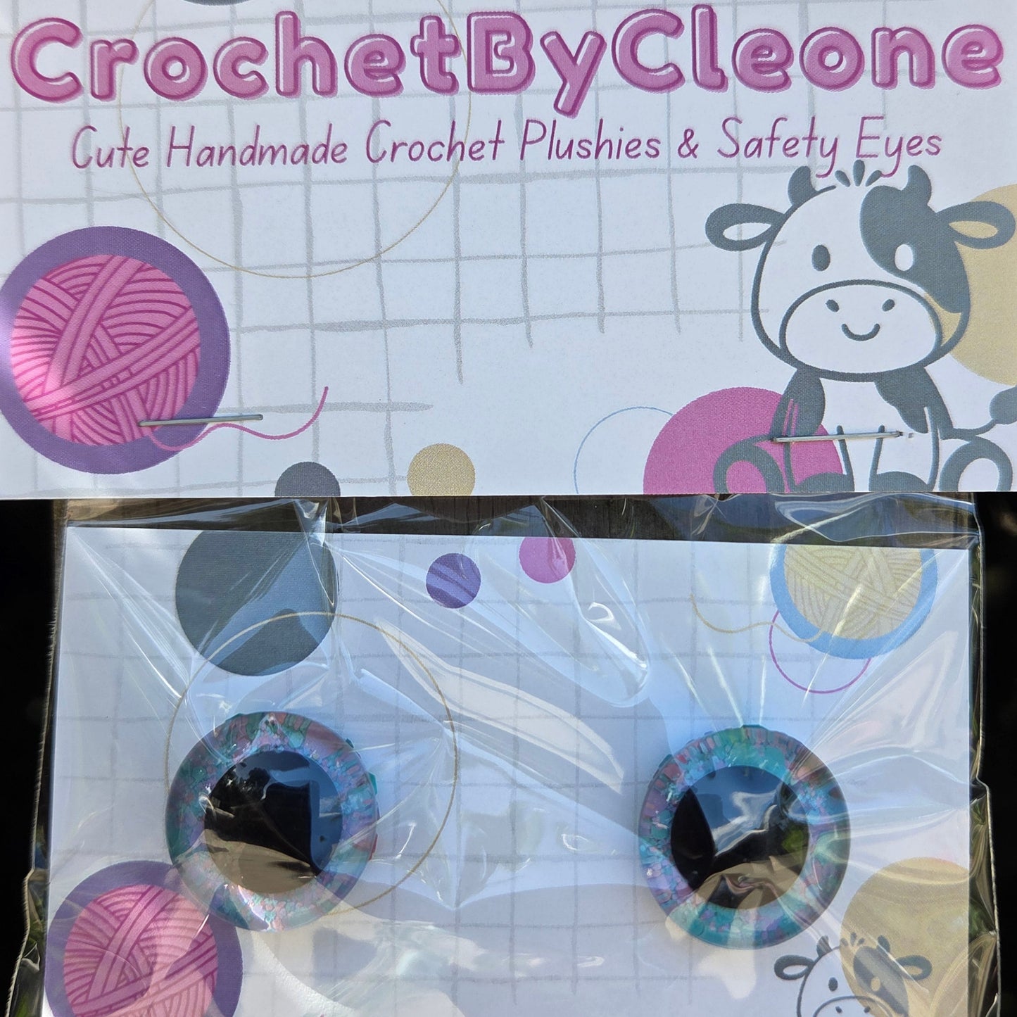 Two packaged crochet safety eyes displayed on a branded card. The left card reads 'CrochetByCleo' and shows the product inside a clear plastic bag on the right.