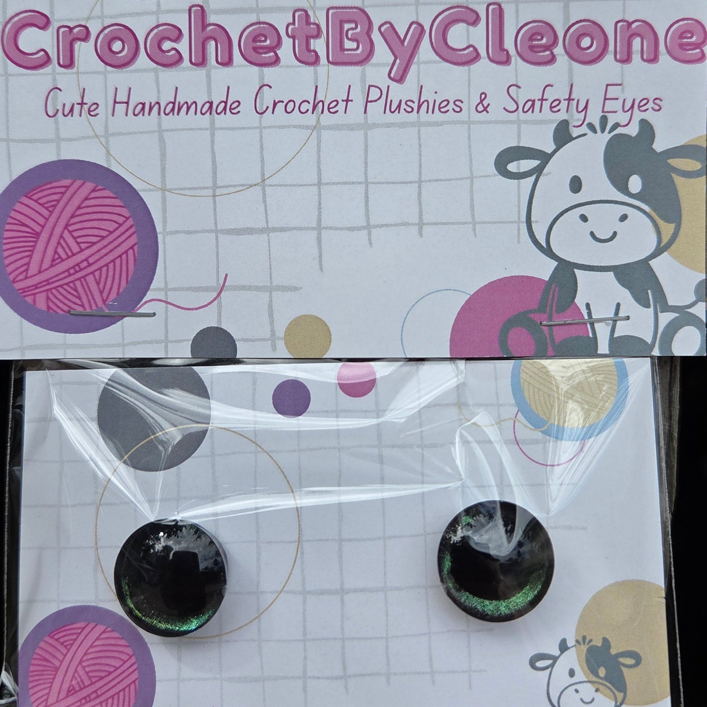 A pair of handmade crochet crochet hooks in a clear plastic sleeve, mounted on a white display card with colorful yarn ball graphics and the brand name 'CrochetByCleo'.