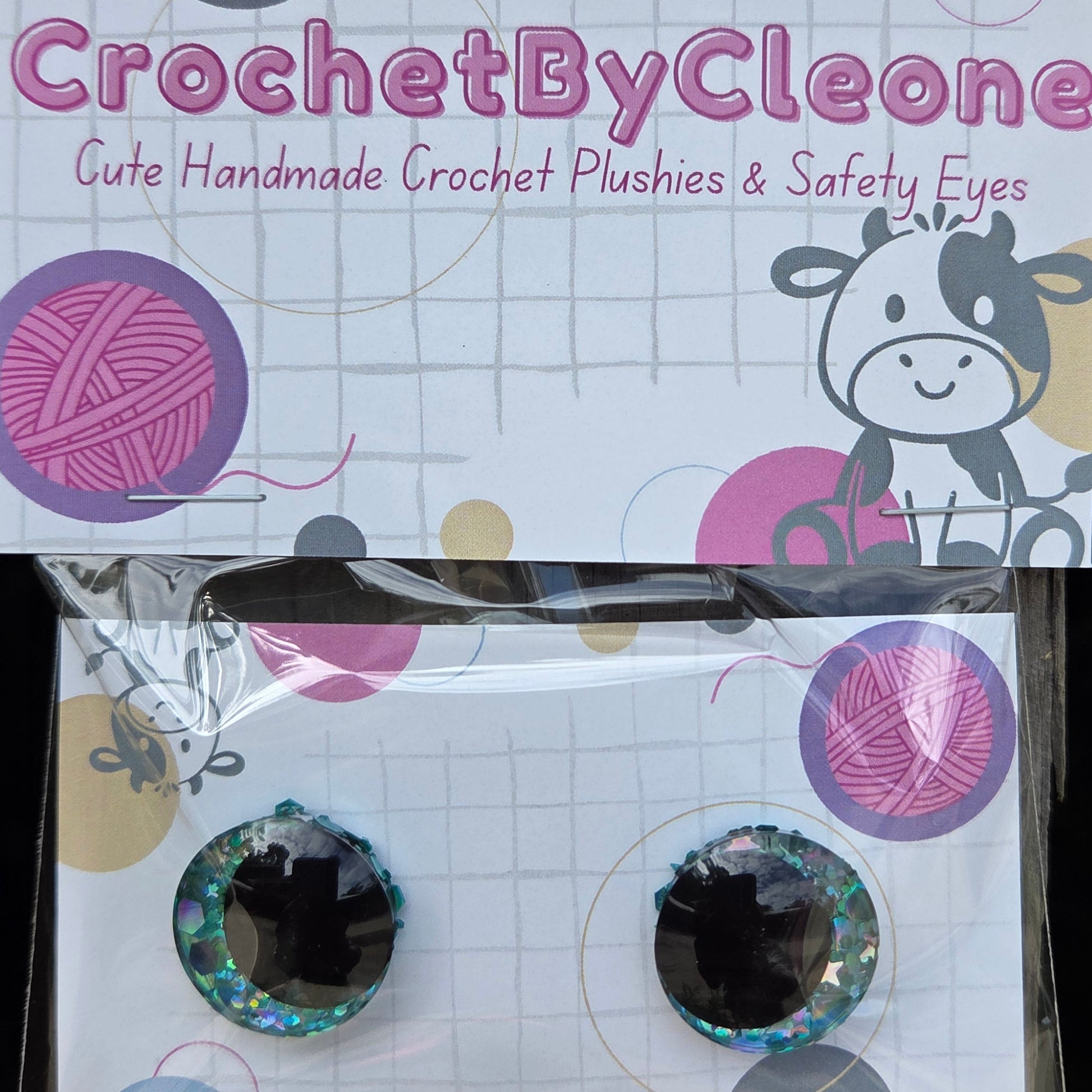 Crochet eyes by CrochetByCleone, featuring a pair of iridescent glittery black crochet eyes in a clear plastic sleeve next to its branded white display card.