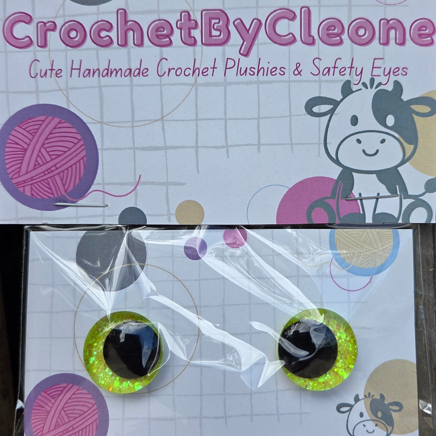 Two novelty safety eyes packaged on a printed display card. The card reads 'CrochetByCleon' and says the items are cute handmade crochet pushpins and safety eyes.